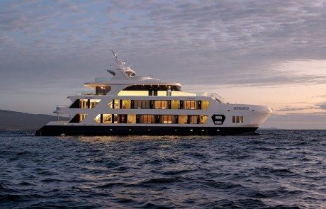 Luxury white motor yacht with multiple decks sailing on calm ocean at sunset