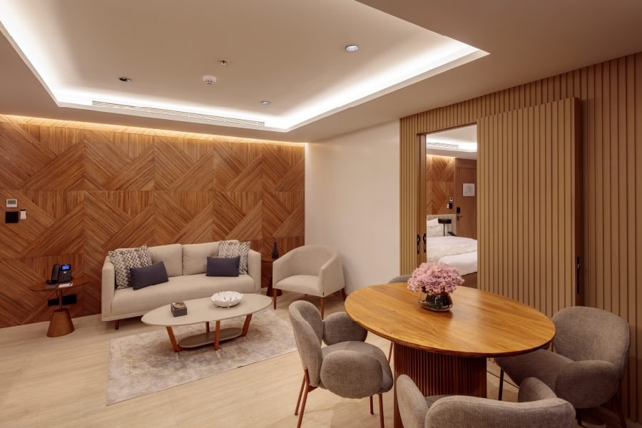 Hotel suite living area with a beige sofa, two armchairs, a round coffee table