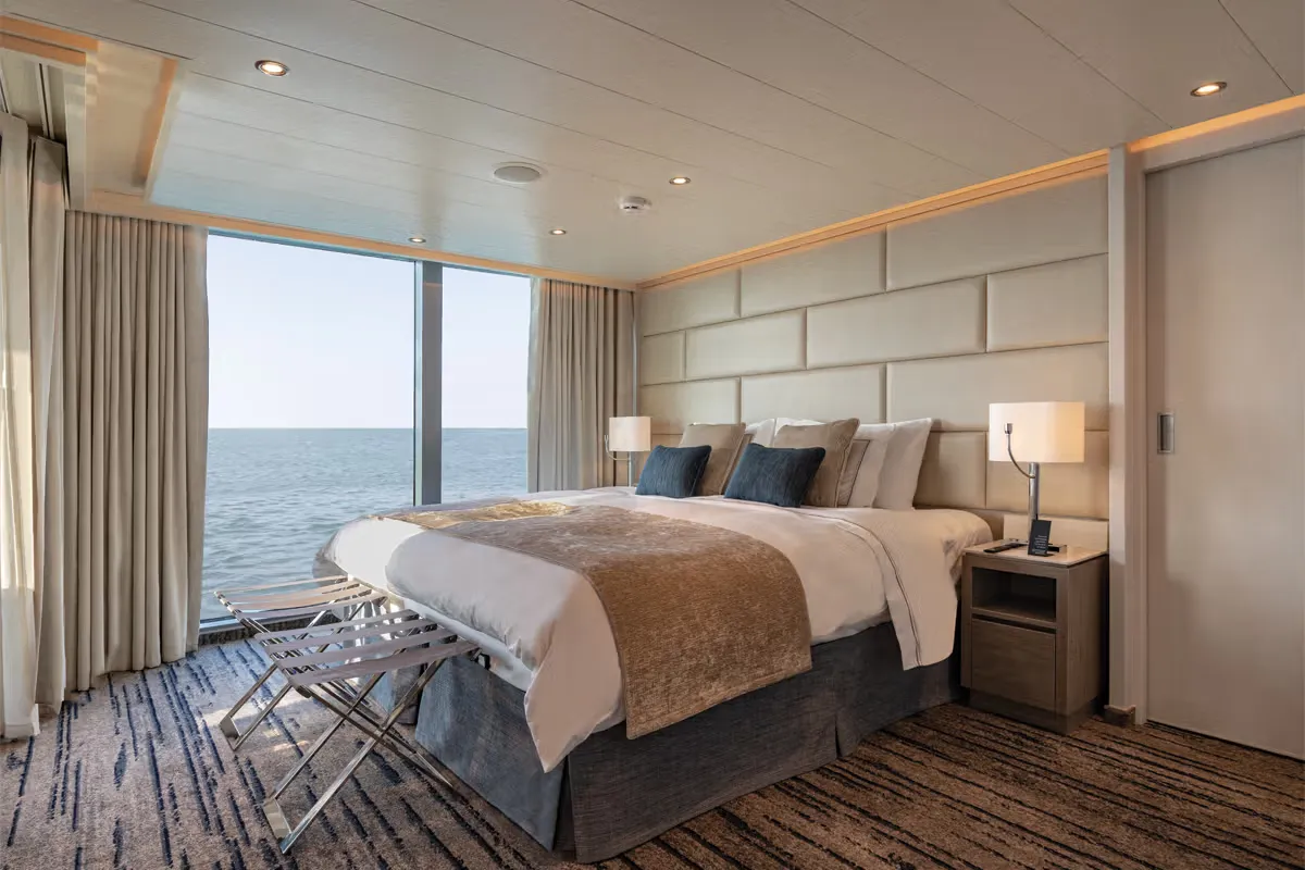 Luxurious ocean-view hotel bedroom with a king-size bed, beige headboard panels