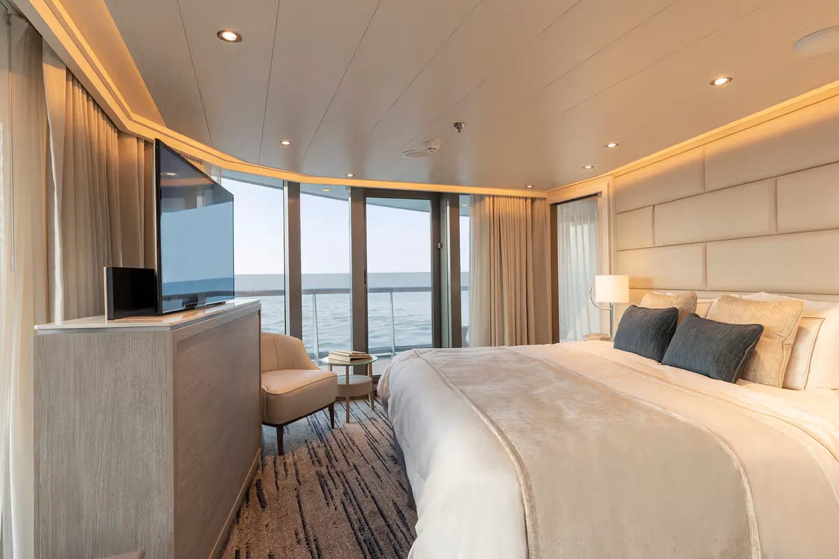 Luxurious ocean-view hotel room with a large bed, TV on a dresser