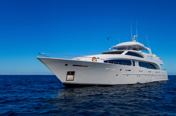 White luxury motor yacht floating on calm blue sea under clear sky; bow toward left, multiple decks visible.