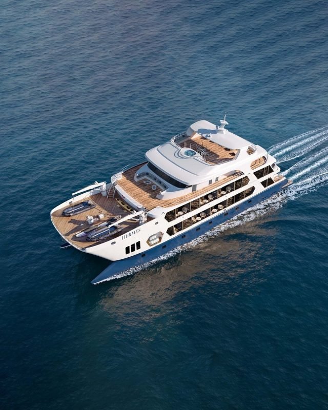 White luxury motor yacht cruising through blue ocean, viewed from above